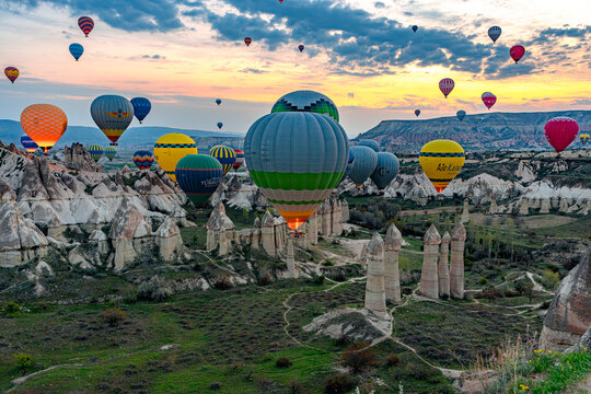 Hot air balloons fly over fairy chimneys in Love Valley during sunrise in Central Anatolia, Turkey