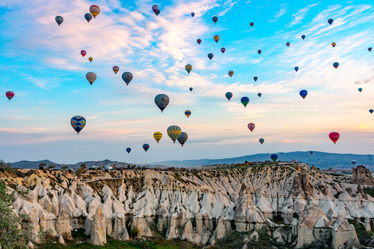 Hot air balloons rise over unique rock formations at sunrise in Love Valley, Cappadocia, Central Anatolia, Turkey