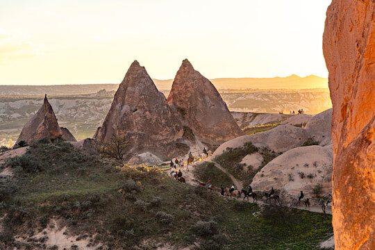 Horseback riders explore fairy chimneys at sunset in Red Valley in Cappadocia, Turkey