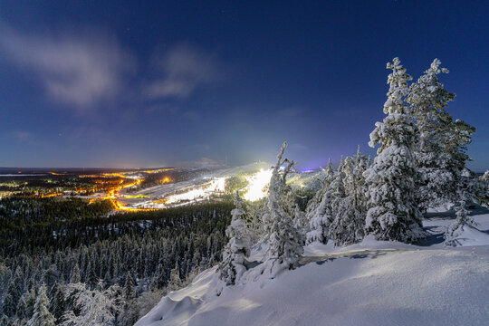Winter night ski area with lights shining on snow-covered slopes in Finland's forest scenery