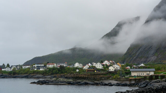 View of houses and mountains in Reine, Lofoten archipelago, Norway during a cloudy day with low visibility and fog
