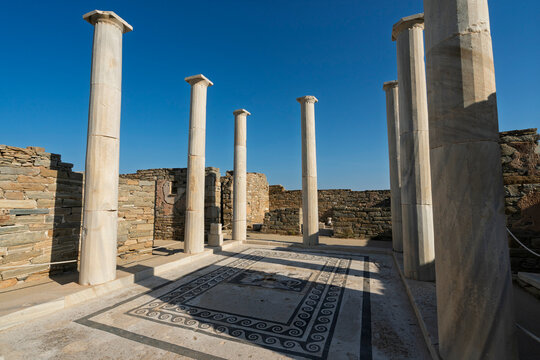 Exploring the House of Dionysos at the Delos archaeological site in the Cyclades region of Greece under clear blue skies