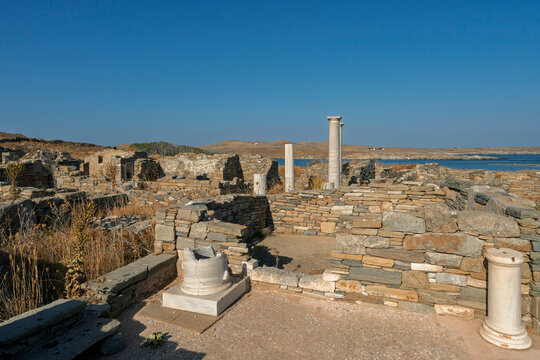 Exploring the ruins of the House of Cleopatra at Delos archaeological site in Cyclades archipelago, Greece under clear blue skies