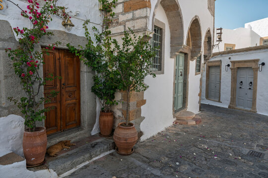 Chora street in Patmos with traditional architecture and a sleeping cat in the afternoon sun
