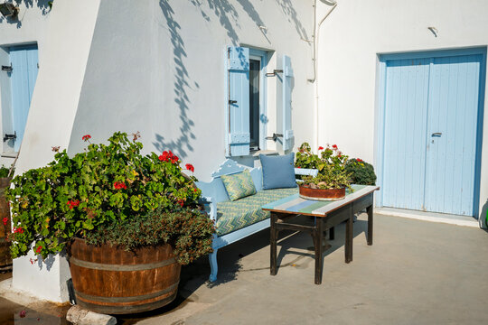 Quiet corner with blue bench and flowers at Nomikos Estate in Santorini, Greece with sunlight shining on the surface