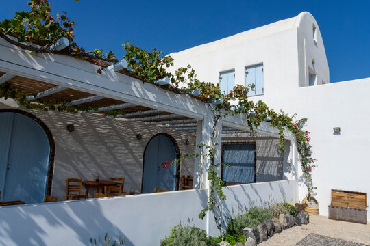 Grapevines grow on a pergola near wooden tables at Nomikos Estate in Vothonas, Greece with clear blue skies above