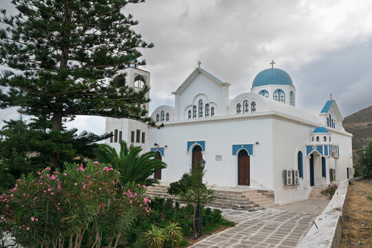 Virgin Orans church stands in Naxos Island surrounded by trees and plants on a cloudy day in Greece
