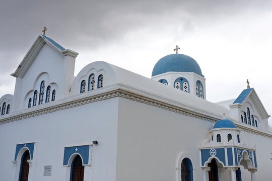 Virgin Orans church located on Naxos Island, featuring classic Greek architecture and blue domes under cloudy sky