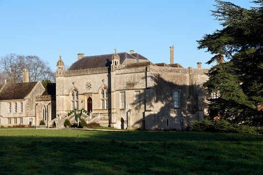 Lacock Abbey shown during daylight with clear skies and green grass in Wiltshire
