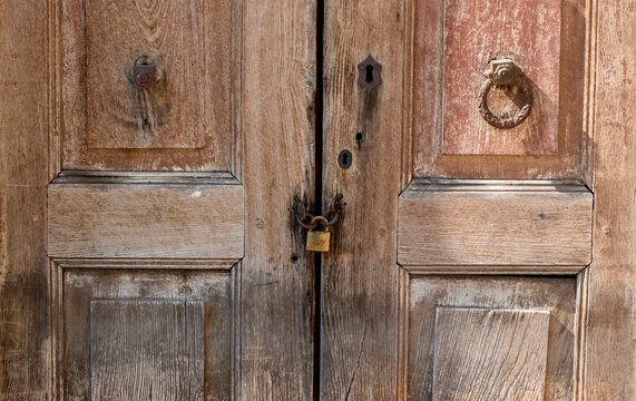 Old wooden doors with a lock and chain in a rural setting during daytime