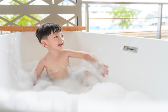 Cute Little Asian Boy Enjoying a Bubble Bath in Modern White Bathtub