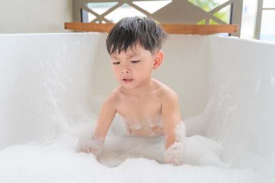 Cute Little Asian Boy Enjoying a Bubble Bath in Modern White Bathtub