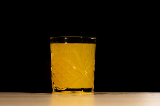 Sparkling Orange Beverage in a Crystal Glass on a Wooden Table with Black Background and Copy Space