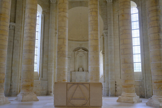 View of choir and chapels in the Royal Abbey of Fontevraud with tall columns and light streaming through windows in Fontevraud, France