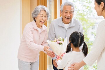 玄関で孫から花束を受け取る笑顔の日本人祖父母