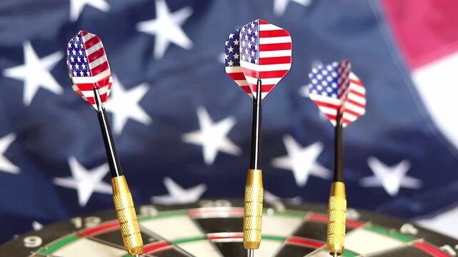 Darts with patriotic flag flights stand fixed in a dartboard while the national flag of the United States waves in the background during a focused indoor recreation activity