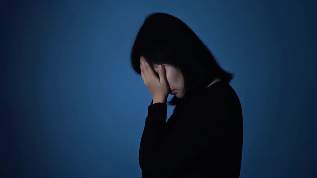 うつむいて立つ女性のシルエット 後ろ姿 青背景