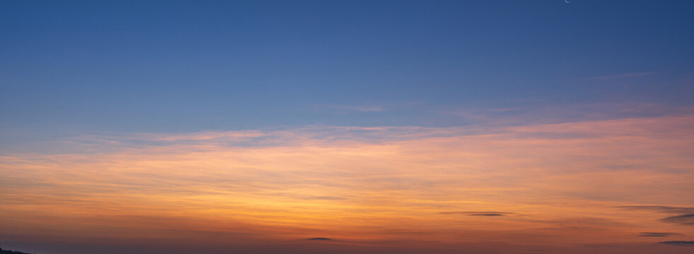 Colorful sunset sky with warm orange clouds and soft blue tones over the horizon.