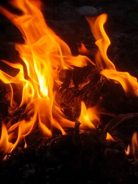 Bright orange flames burning paper debris close up