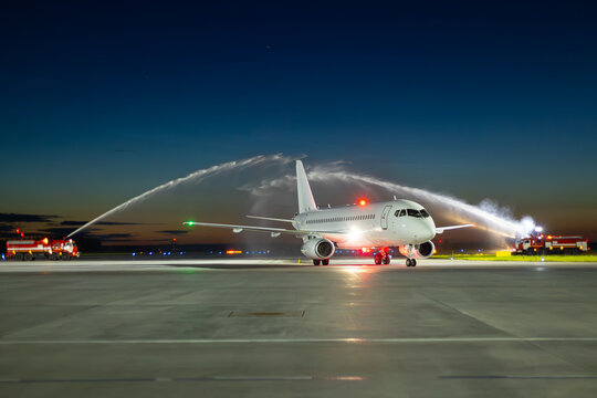 Water arch for first visit white passenger plane at the night airport