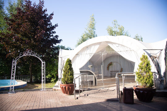 White party tents in a park with trees and a road in the background.