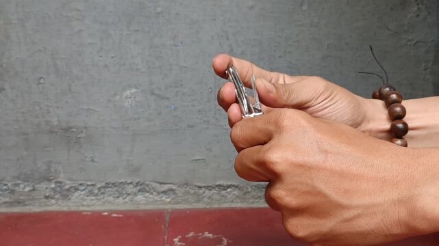 Someone trimming their fingernails with a nail clipper at home. A daily hygiene and self-care routine in a clean room.