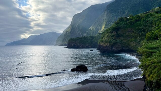 Beautiful view of Seixal Beach with black volcanic sand, Atlantic Ocean and green mountains on Madeira Island, Portugal.