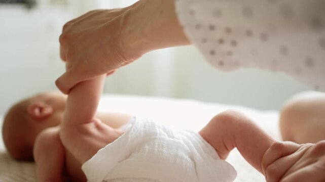 Close up of a mothers hands gently massaging her newborn baby's tiny legs and feet to help with digestion and relieve colic, fostering bonding and providing comfort and wellness