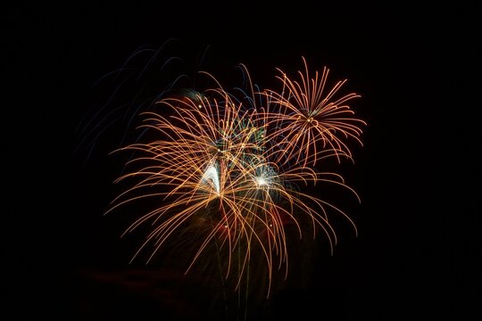 gold, blue and green streams of light from the burst of exploding fireworks