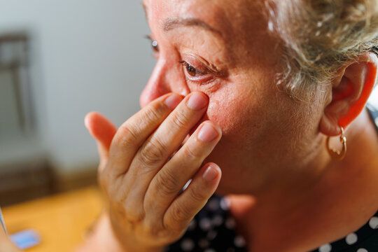 Close up of mature older female touching under eye wrinkles.