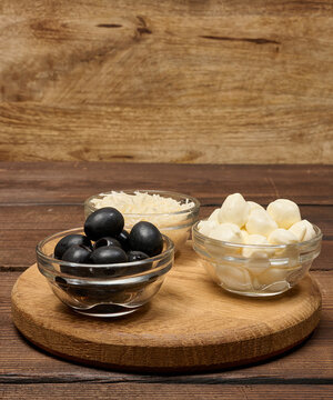 Fresh mozzarella balls, pitted olives and grated cheese in glass bowls