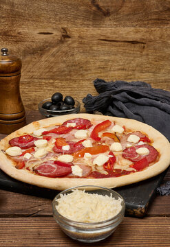 Pizza with salami, ham and mozzarella cheese on parchment