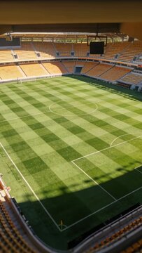 Vertical video: Tilting camera revealing empty pitch at stadium to show corner flag and monitor