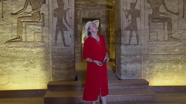 Woman in a red dress exploring the temple in Abu Simbel, Egypt.