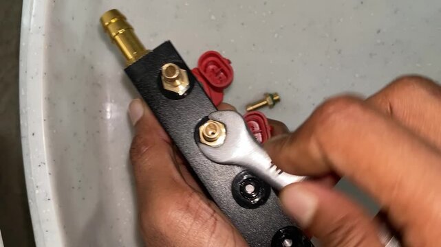 Tightening a brass nozzle on an injector rail with a 10mm wrench