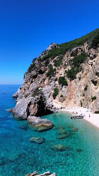 Aerial view of the wild Gyali beach in Corfu, Greece, with dramatic high cliffs and crystal clear turquoise sea.

