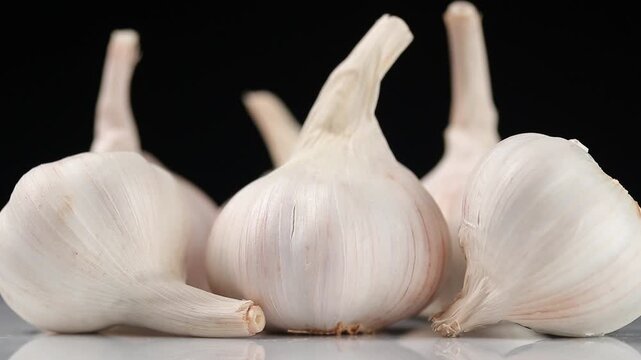 Fresh garlic bulb slowly rotating on a black background.