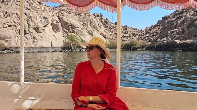 A woman in a red dress exploring the ruins of the Philae Temple, Aswan, Egypt.