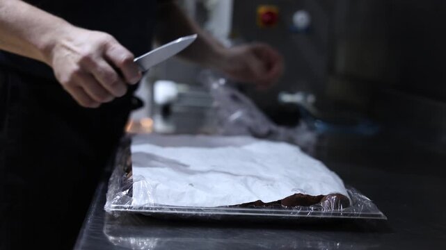 Pastry chef removing plastic wrap from a tray of freshly made chocolate cocoa truffles
