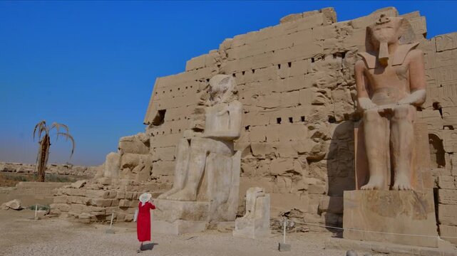 A woman in a red dress exploring the ruins of the Karnak Temple, Luxor, Egypt.