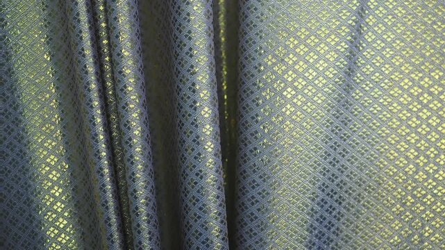 Curtains featuring an intricate diamond pattern known as lai khao lam tad combine geometric shapes with shimmering gold threads.