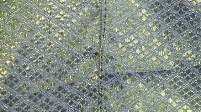 Curtains featuring an intricate diamond pattern known as lai khao lam tad combine geometric shapes with shimmering gold threads.