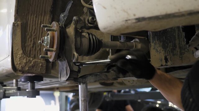 A detailed view of a mechanic working on a car's wheels at a repair shop. He takes apart the wheel to perform internal repairs. The process of fixing wheels, brakes, and shock absorbers.