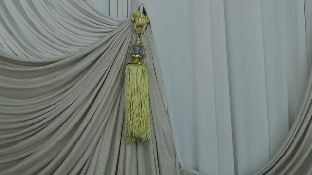 Gold tie-back curtains featuring tassels and crystal-like accents for a luxurious look.