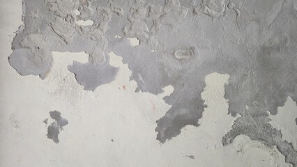 Old cement wall with peeling paint and cracked plaster texture. Weathered concrete surface with flaking wall paint, showcasing a rugged distressed texture layers. © Kawee