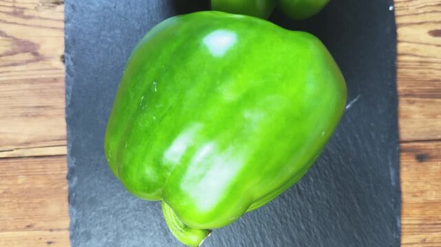 Fresh green bell peppers on a black slate flat plate