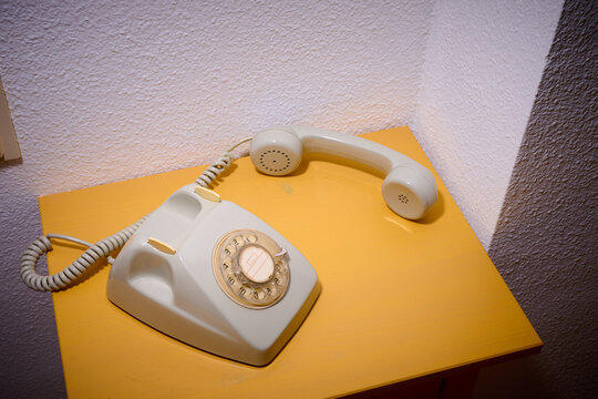 Close-up of an old rotary dial telephone on a yellow wooden table.