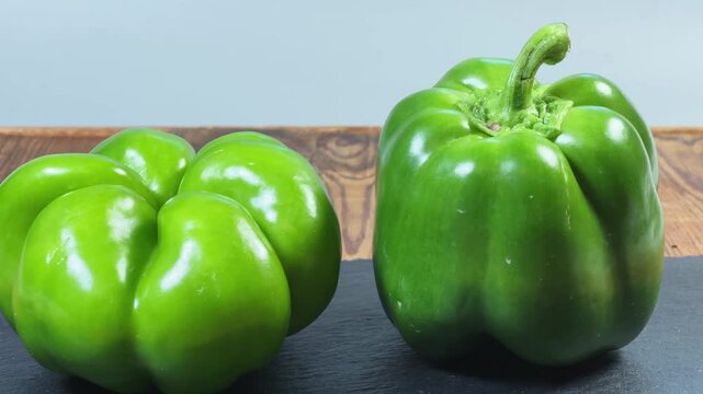 Fresh green bell peppers on a black slate flat plate