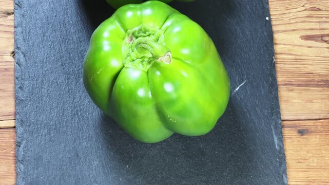 Fresh green bell peppers on a black slate flat plate