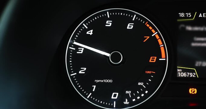 Close-up shot of a modern car digital tachometer needle moving rapidly as the engine revs up, displaying changing RPM data.